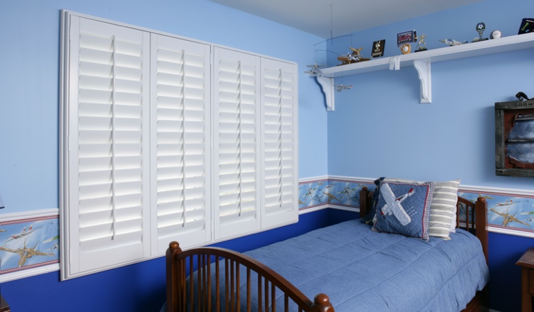 Large plantation shutters covering window in blue kids bedroom in Chicago 
